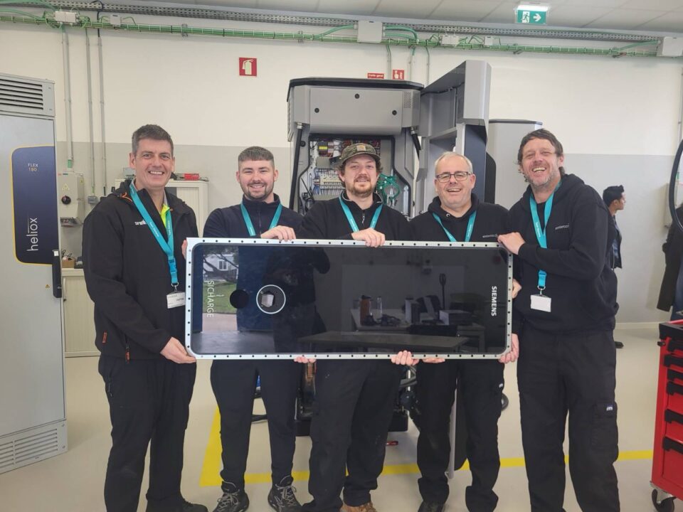 Evolt team members pose with a panel from an EV charger