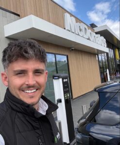 A man standing beside an Evolt Charging EV charger located at a McDonald's restaurant.