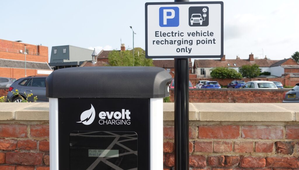 The top third of an Evolt Charging EV charger along with EV signage.