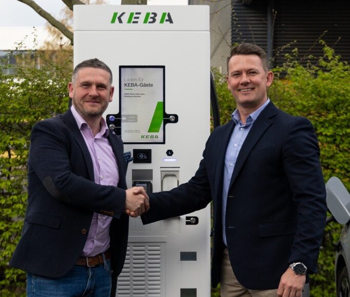 Darren and Justin shaking hands in front of a Keba DC EV charger